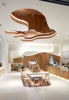 the interior of a restaurant with wooden tables and stools in front of an open counter