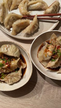 dumplings with sauce and chopsticks in white bowls on a wooden table top