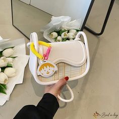 a person holding a white purse with flowers in front of it and a mirror behind them