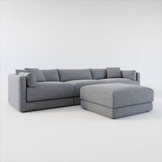 a large gray sectional couch sitting on top of a white floor next to a footstool