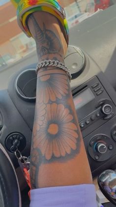 a person's arm with a flower tattoo on it and a chain around the wrist