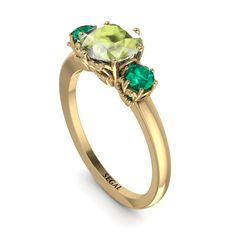 a yellow gold ring with two green stones on the front and one stone in the back