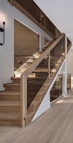 an empty room with wood floors and white walls, along with a staircase leading up to the second floor