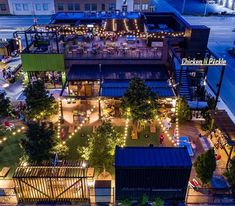 an aerial view of the outside of a restaurant at night with outdoor seating and lights