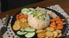 a plate with crackers, carrots, cucumbers and crackers on it