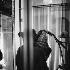 a woman is taking a shower in front of a mirror with her hands on the faucet