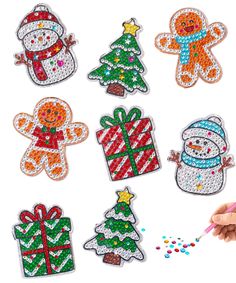 a hand holding a pencil in front of some christmas decorations on a white surface with glitters