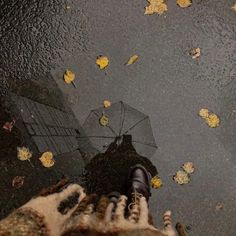 a person standing in the rain with their feet up and holding an umbrella over them