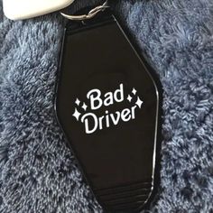 a black keychain with the words bad driver on it