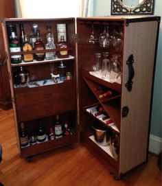 an open cabinet filled with liquor bottles and glasses on top of a hard wood floor