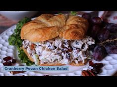 a croissant sandwich with chicken salad and pecans on a plate next to grapes