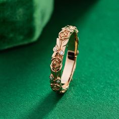 a gold ring with flowers on it sitting on a green surface