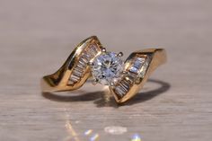 a close up of a gold ring with a diamond in it on a wooden surface