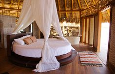 a bed with white sheets and pillows in a room that has wood flooring on the walls