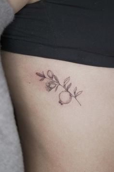 a woman's stomach with a rose tattoo on her left side ribcage