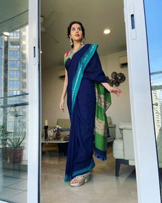 a woman standing in an open doorway wearing a blue sari