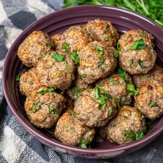 a white plate topped with meatballs next to mushrooms and parsley on a table