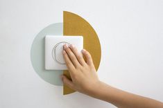 a person turning on a light switch in a room with white walls and gold circles