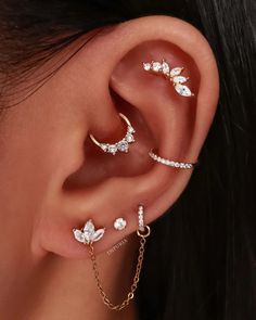 a woman wearing ear piercings with leaves and chains on her ears, both in gold