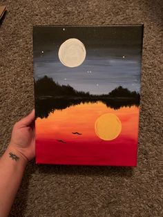 someone is holding up a painting on the floor with a full moon in the background