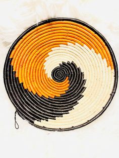 an orange and black woven basket on white furnishing, with the center circle made up of smaller circles