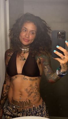 a woman with tattoos taking a selfie in the mirror