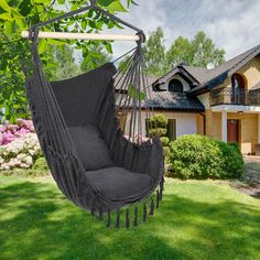 a black hammock chair hanging from a tree in front of a large house