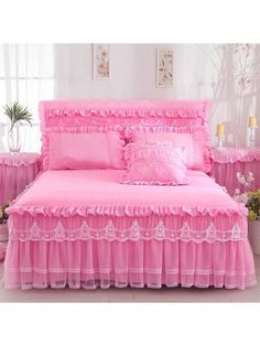 a pink bed with ruffled bedspread and pillows