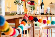 the table is set with colorful pom - poms and wine glasses on it