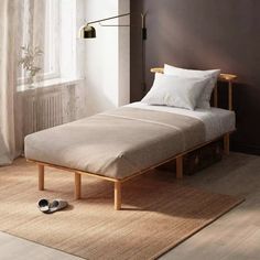 a bed sitting on top of a wooden floor next to a window