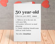 a card with the words 40 year old on it sitting on a wooden table next to some paper hearts