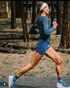 a woman running in the woods with trees behind her