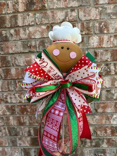 a person holding up a christmas ornament in front of a brick wall