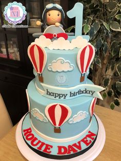 a birthday cake for a one year old boy with hot air balloons and clouds on top