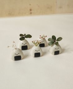 four small white vases with plants in them