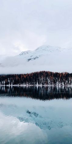 a lake surrounded by snow covered mountains and trees