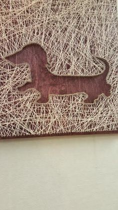 a wooden dachshund cut out on top of some white string art paper