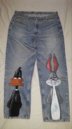 a pair of jean pants with cartoon characters painted on the side and one has a black cat