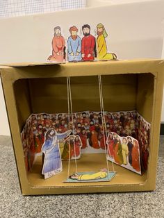 an open cardboard box with paper cutouts of jesus and other figures on the inside