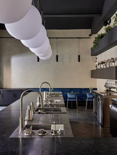 an industrial style kitchen with black counter tops and stainless steel appliances, along with hanging lights