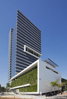 an office building with a green wall on the front and side of it's facade