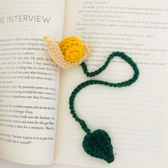 a crocheted bookmark with a yellow flower on it sitting next to an open book