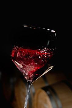 a glass of wine sitting on top of a wooden barrel