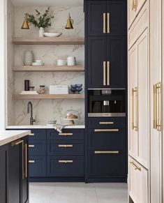 a kitchen with blue cabinets and gold pulls on the doors, white marble countertops