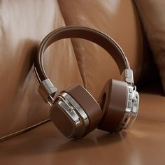 a pair of headphones sitting on top of a brown leather couch next to pillows