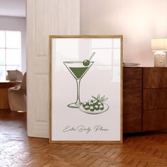 a framed poster with a martini glass and olives on the table next to it