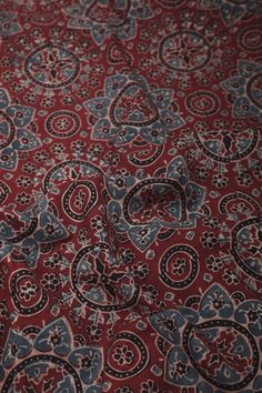 a red and blue paisley print fabric on a tablecloth with an intricate design in the center