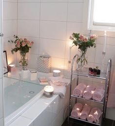 a bathroom with candles, towels and flowers on the bathtub counter top in front of it