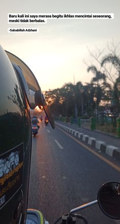 the view from a motorcycle driving down a road with cars on it and trees in the background