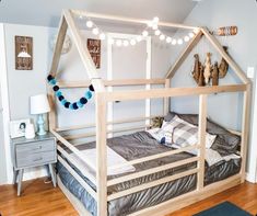 a child's bed with a tent on top and lights strung from the ceiling